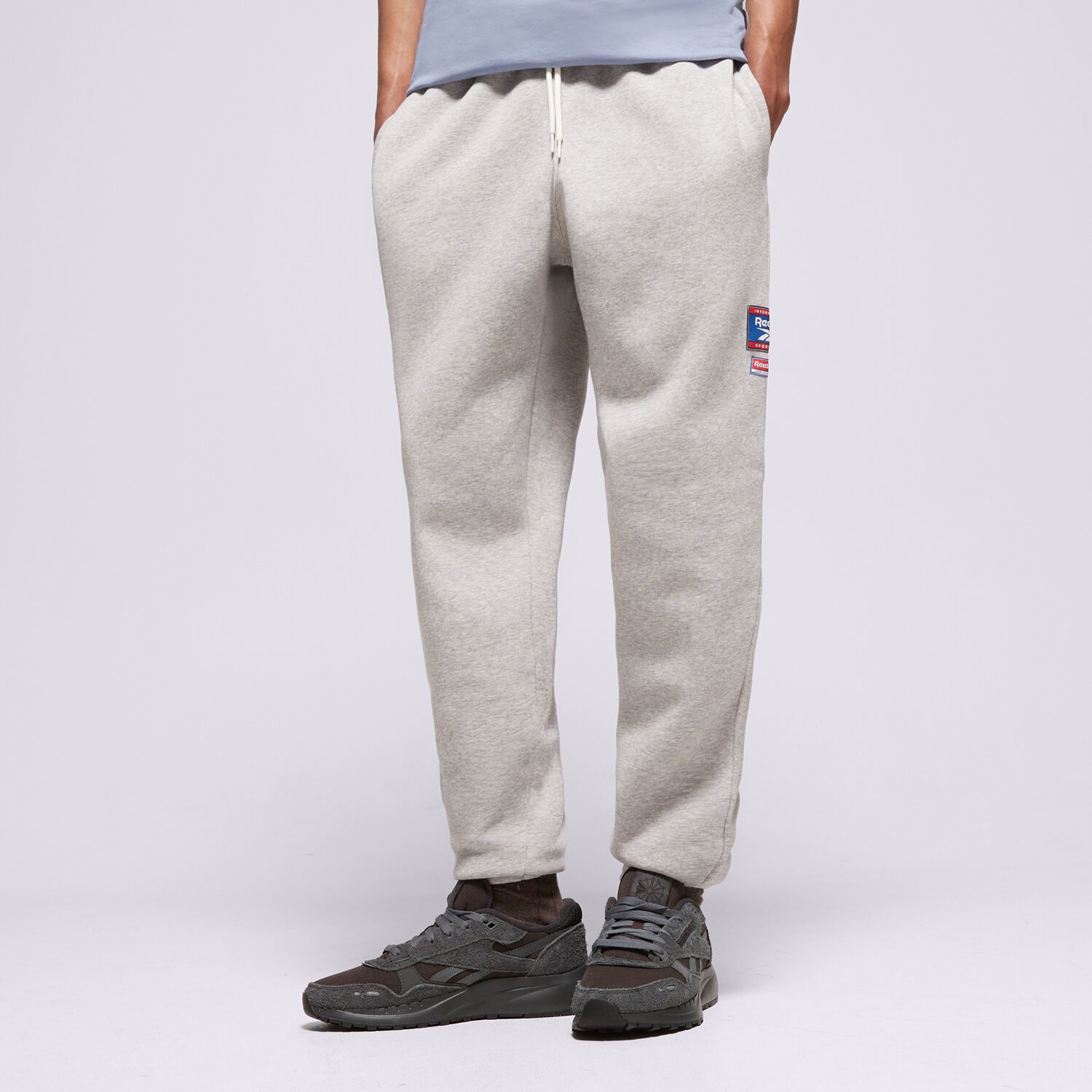 Bărbați pantaloni REEBOK PANTALONI  RI BADGE 100205445 Gri